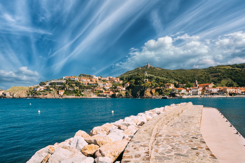 Plage Collioure vue depuis le port avec ciel spectaculaire et village en arrière-plan