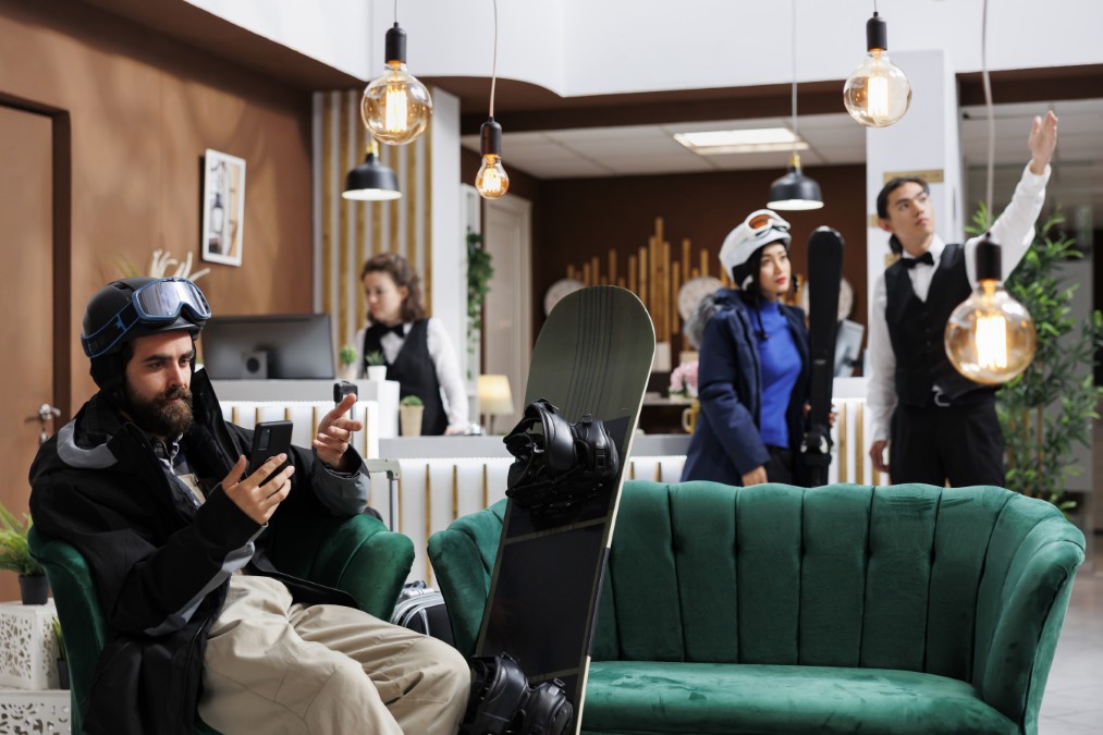 Un skieur attend dans le hall d'accueil moderne d'un hôtel ou d'une résidence de standing.