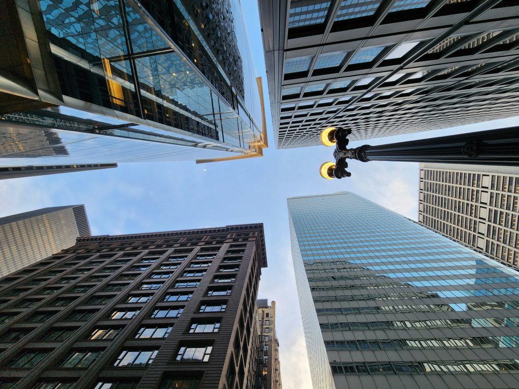 Perspective ascendante de gratte-ciel modernes en verre et acier, symbolisant la valorisation immobilière dans un quartier dense.