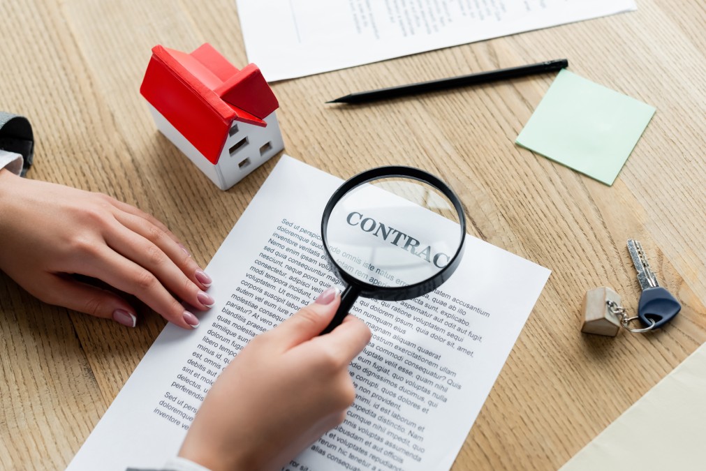 Personne examinant un contrat immobilier à la loupe pour détecter les pièges de la location accession.