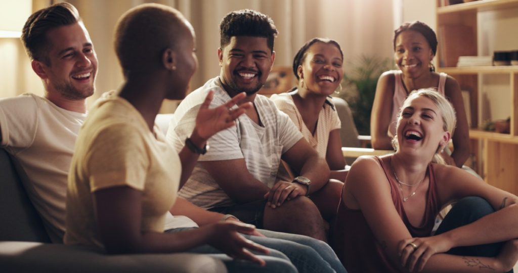 Groupe de jeunes adultes partageant un moment de convivialité dans le salon d'une colocation à Londres.